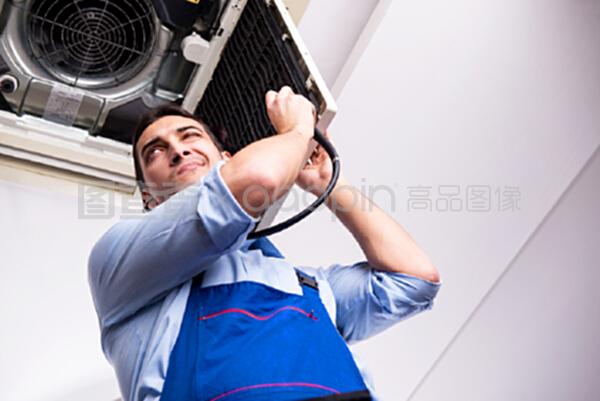 修理天花板空调设备的年轻修理工
